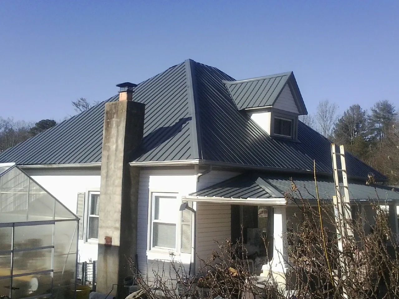 Dark blue standing seam metal roof on a white farmhouse with dormer — Slate & Tile Roof Repair by Roofing Brothers in Elverson
