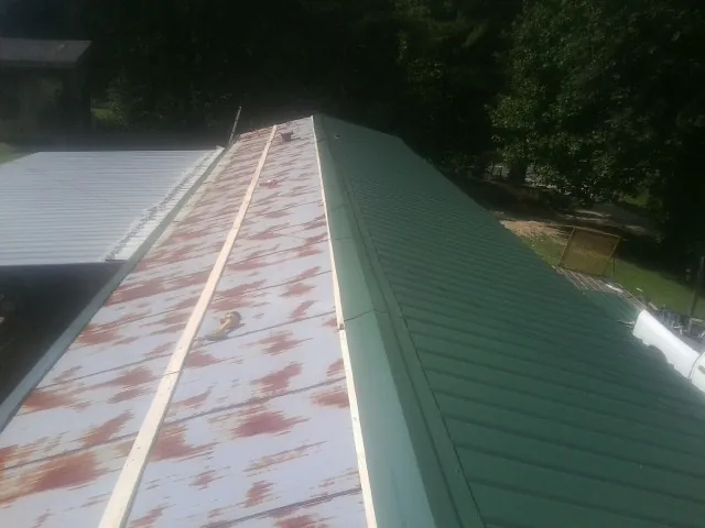Old rusted panels beside newly installed green metal roofing — Wind Damage Roof Repair by Roofing Brothers in Elverson