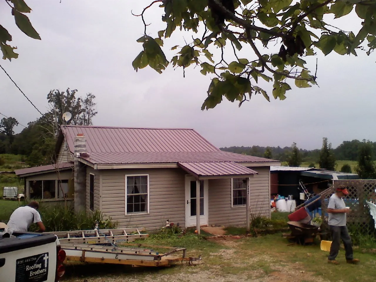Crew finishing a mauve metal roof on a small farmhouse in Elverson