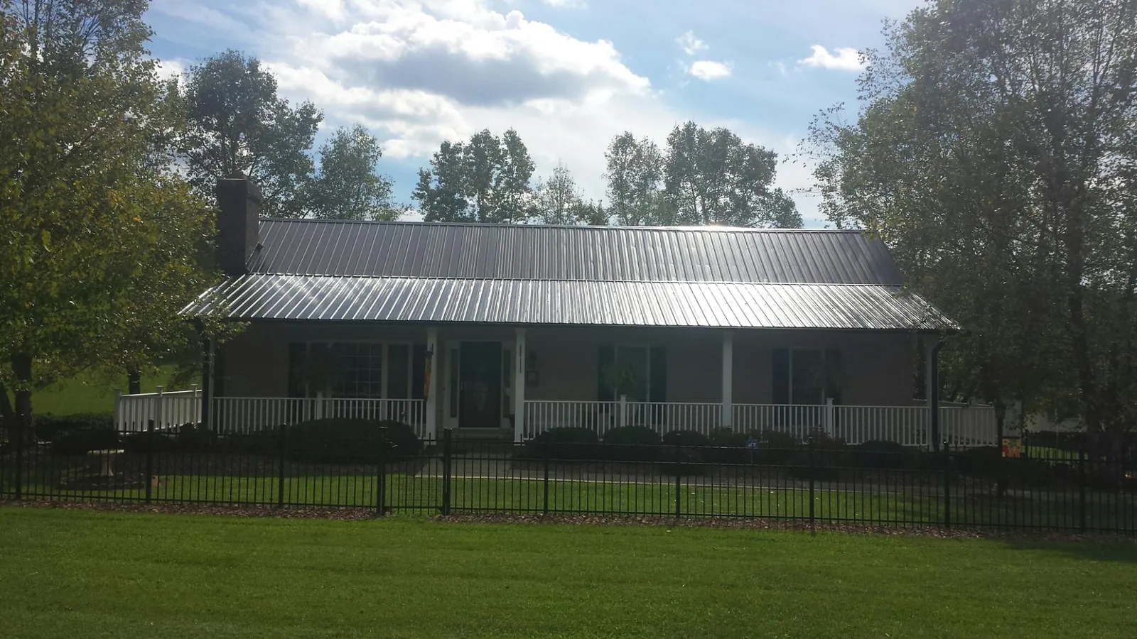 Gray metal roof on a brick ranch with a full width front porch — Gutter Guard Installation work by our crew in Elverson