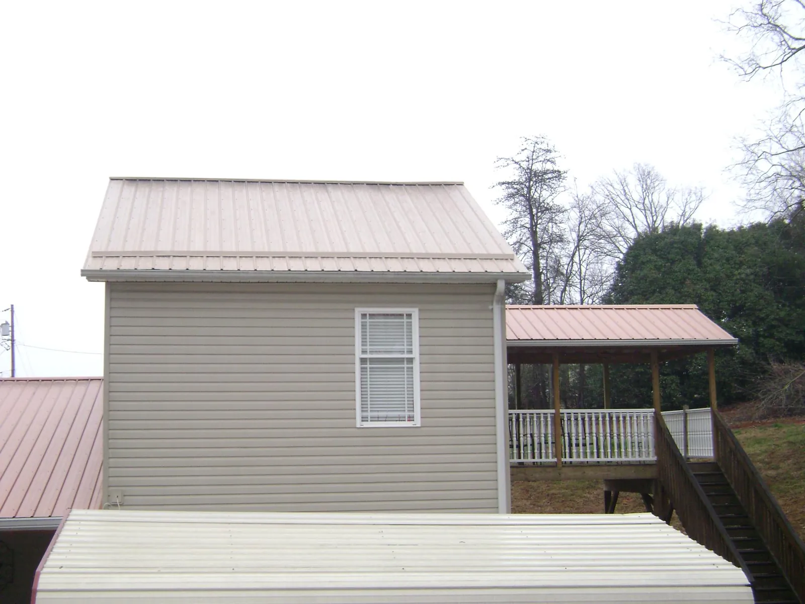 Tan metal roofs on a two story addition and attached porch, from a Roof Replacement job in Elverson