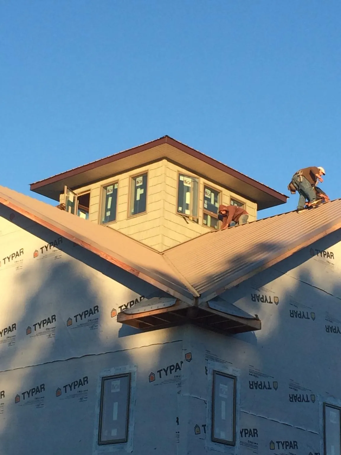 Roofers working around a rooftop cupola on a new metal roof at sunset — Roof Waterproofing in Elverson by Roofing Brothers